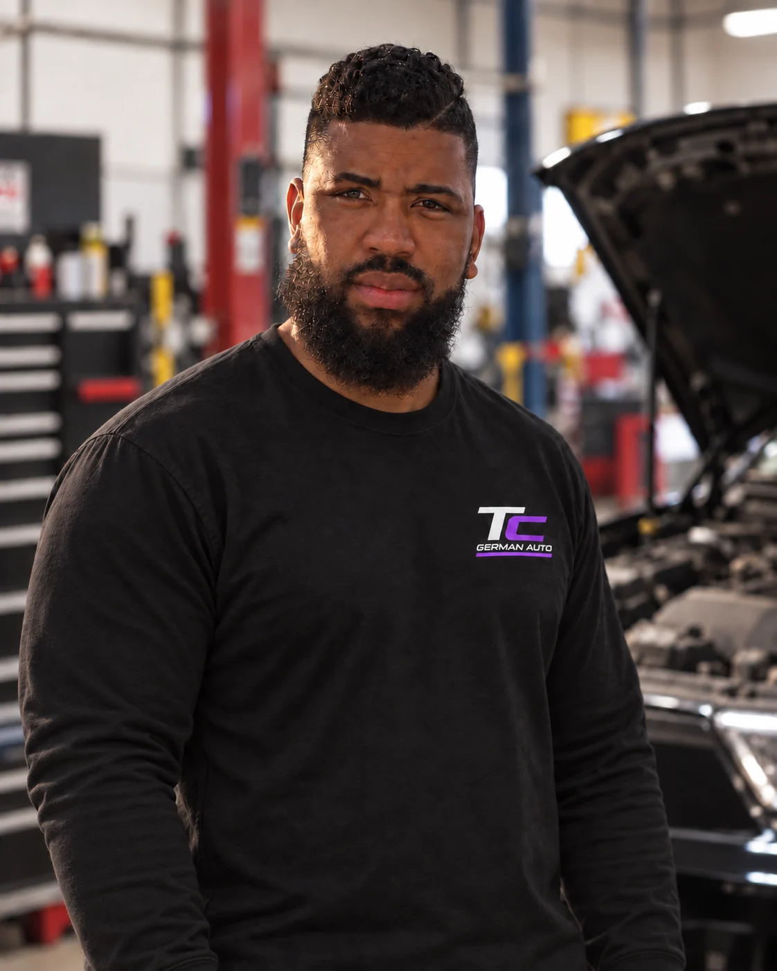 Roy in mechanic gear beside a car